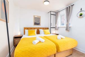 deux lits dans une chambre avec des draps jaunes et des oreillers jaunes dans l'établissement Spacious 5 Bedroom 2 Bathroom Home with 12 Beds and Private Driveway Parking, à Manor
