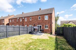 une maison en briques avec une clôture devant elle dans l'établissement Spacious 5 Bedroom 2 Bathroom Home with 12 Beds and Private Driveway Parking, à Manor 16 autres photos