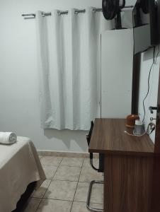 a room with a bed and a desk and a curtain at Quarto Sakura na Sakura House in Indaiatuba +1 photo