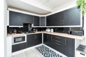 a kitchen with black cabinets and white appliances at Spacious 4 Bedroom House with 8 Beds and Private Driveway Parking in Heeley