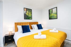 a bedroom with two beds with yellow sheets and blue pillows at Spacious 4 Bedroom House with 8 Beds and Private Driveway Parking in Heeley