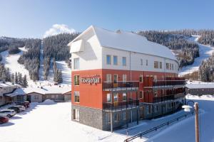 a building in the snow with a mountain in the background at Apartments Klövsjöfjäll in Klövsjö