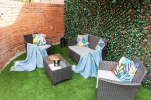 a patio with three chairs and a table and a wall at 4 Bedroom House with 2 Bathrooms - Back Garden with Outdoor Seating Sleeps 7 in Heeley