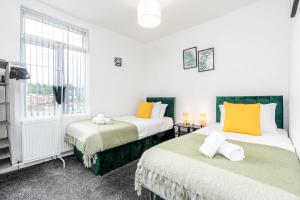 two beds in a room with two windows at 4 Bedroom House with 2 Bathrooms - Back Garden with Outdoor Seating Sleeps 7 in Heeley