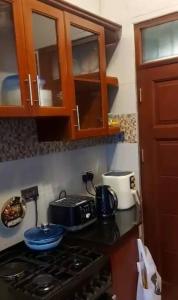 une cuisine avec une plaque de cuisson au four et des placards en bois dans l'établissement Daud Monica Staycation Home, à Manyema