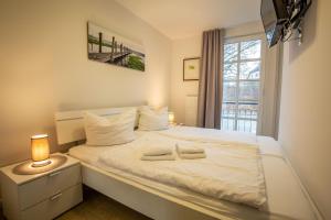 a bedroom with a large white bed with a window at Residenz am Balmer See - Kleine Auszeit - BS 21 mit Wellnessbereich in Balm