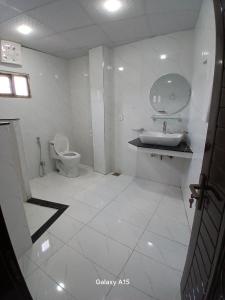 Un baño blanco con inodoro y lavabo. en Sky Mount Hotel Patriata, en Patriata