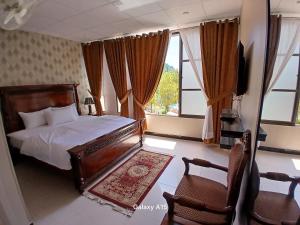 Un dormitorio con una cama y una silla y ventanas. en Sky Mount Hotel Patriata, en Patriata