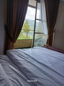 Un dormitorio con una cama y una ventana con vistas. en Sky Mount Hotel Patriata, en Patriata