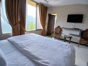 Un dormitorio con una cama y dos sillas y un televisor. en Sky Mount Hotel Patriata, en Patriata 16 fotos más