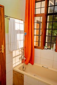a bathroom with an orange curtain and a bath tub at Amani Farmhouse in Usa River +76 photos