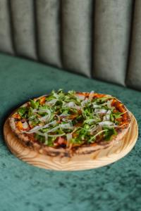 a pizza sitting on a wooden plate on a table at Charles Hope Boutique Hometel in Cape Town