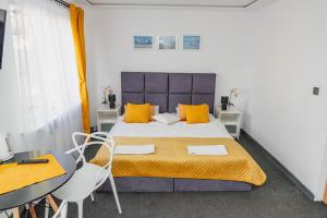 a bedroom with a bed with orange pillows and a table at Ośrodek Wypoczynkowy Leśne Ustronie in Witnica