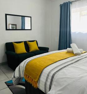 a bedroom with a bed with yellow pillows and a couch at Hlatsi Bushview Apartments & Safaris in Hazyview +55 photos