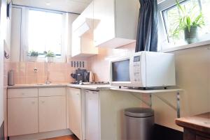 a white kitchen with a microwave on a counter at Hello Zeeland - Halve Maanstraat 10 in Oostkapelle