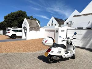 a white scooter parked in a parking lot at Adrift Guesthouse in St Francis Bay
