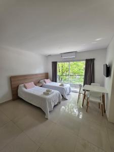 a bedroom with two beds and a table and a window at Aparts Magallanes in Pilar