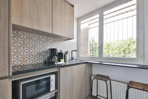 Eine Küche mit Fernseher, Fenster und Arbeitsplatte in der Unterkunft Louis Vicat 4 - CI - Apartment for 2 Parc Expo Porte de Versailles in Paris