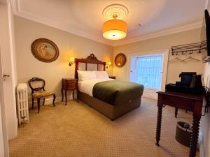 ein Schlafzimmer mit einem Bett und einem Tisch und einem Fenster in der Unterkunft Cashel Regency Townhouse in Cashel