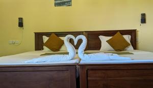 two swans shaped like hearts sitting on two beds at Tiara Elephant Lodge in Habarana