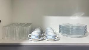 une rangée d'assiettes et de tasses sur une étagère dans l'établissement Casa ampla próxima ao centro, à Dourados