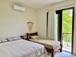 1 Schlafzimmer mit 2 Betten und einem Fenster mit Balkon in der Unterkunft Vila Bambu – by Refúgio Hospedagens in Areia