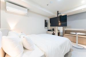 a bedroom with a white bed and a flat screen tv at 스테이쉼 발산 in Seoul