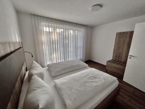 a bedroom with a bed with white sheets and a window at WeberHof Appartements in Burg