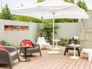 un patio con sillas y una sombrilla blanca en Hotel ibis Guimaraes, en Guimarães