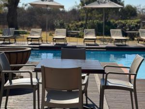 einen Holztisch und Stühle neben einem Pool in der Unterkunft Tshikwalo Guest House in Klipdrift + 8 Fotos