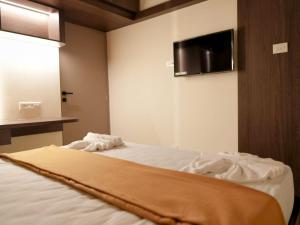 ein Schlafzimmer mit einem Bett und einem Fernseher an der Wand in der Unterkunft Amaira Studio living - Coimbatore in Coimbatore