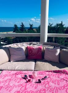 a couch with pink and white pillows on a balcony at Тематичен Пентхаус Несебър България in Nesebar