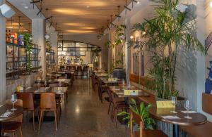 un restaurant avec des tables, des chaises et des plantes dans l'établissement Hotel Bazaar - Fattal Colors, à Tel Aviv