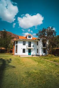 ein weißes Haus mit einem orangefarbenen Dach auf einem Feld in der Unterkunft Casa Julia in Huayllabamba