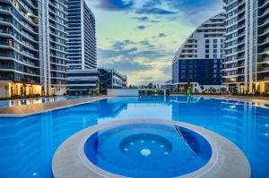 a swimming pool in a city with tall buildings at Студия в White Sails видовая in Batumi