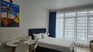 a bedroom with a bed and a table and a window at Студия в White Sails видовая in Batumi +12 photos