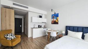 a bedroom with a bed and a table and a kitchen at Студия в White Sails видовая in Batumi