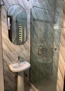 ein Badezimmer mit Waschbecken und Dusche mit Spiegel in der Unterkunft Oystershell Apartments in Gbogije