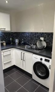une cuisine avec une machine à laver et un évier dans l'établissement Room in Stylish City Apartment, à Colindale