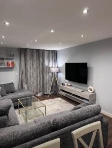 un salon avec deux canapés et une télévision à écran plat dans l'établissement Room in Stylish City Apartment, à Colindale