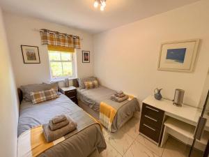 a bedroom with two twin beds and a desk at Railway Cuttings in Falstone +4 photos