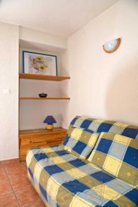 ein Schlafzimmer mit einem Bett mit einer blau-gelben karierten Decke in der Unterkunft Les myosotis in Bolquere