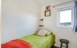 ein kleines Schlafzimmer mit einem grünen Bett und einem Fenster in der Unterkunft Strandhuis `Meerzicht` in Lauwersoog