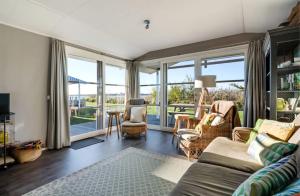 ein Wohnzimmer mit Sofa, Stühlen und Fenstern in der Unterkunft Strandhuis `Meerzicht` in Lauwersoog