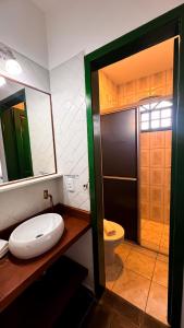 ein Badezimmer mit Toilette, Waschbecken und Spiegel in der Unterkunft Pousada in Bombinhas + 44 Fotos
