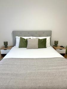 une chambre avec un grand lit blanc avec des oreillers verts dans l'établissement 22nd Floor Luxury City Centre Apartment, à Belfast