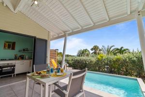 a patio with a table and chairs next to a swimming pool at Bungalow Lagoon in Fouché +4 photos