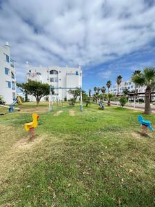 a park with three play equipment in the grass at Apartamento in M'diq