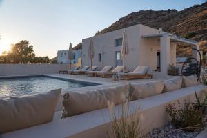 a swimming pool with lounge chairs and a house at Siroco Patmos in Patmos