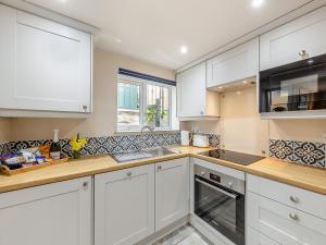 a kitchen with white cabinets and a sink at The Cottage At Number One in Caerwys